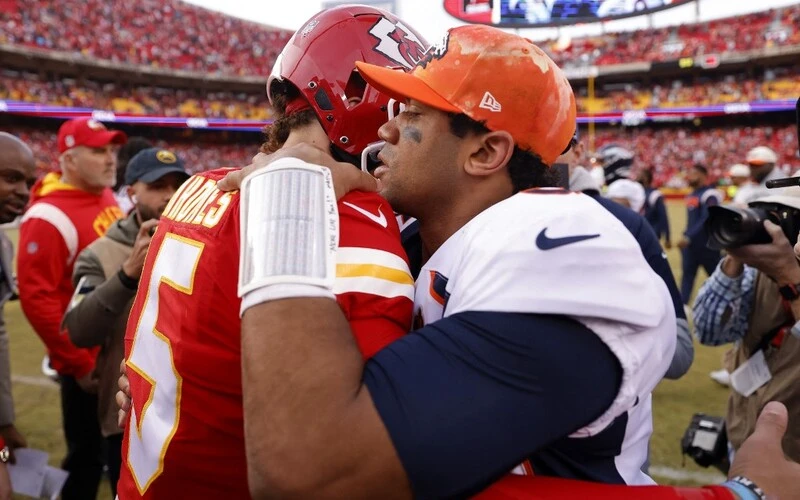 Patrick Mahomes #15 of the Kansas City Chiefs and Russell Wilson #3 of the Denver Broncos embrace after the game at Arrowhead Stadium.