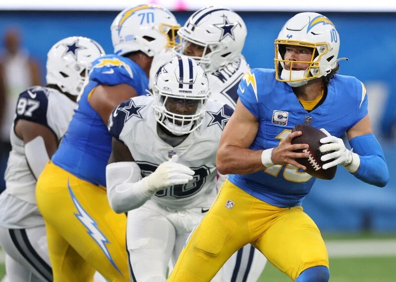 Justin Herbert #10 of the Los Angeles Chargers scrambles from DeMarcus Lawrence #90 of the Dallas Cowboys. The Chargers vs Chiefs Betting Odds are ready.