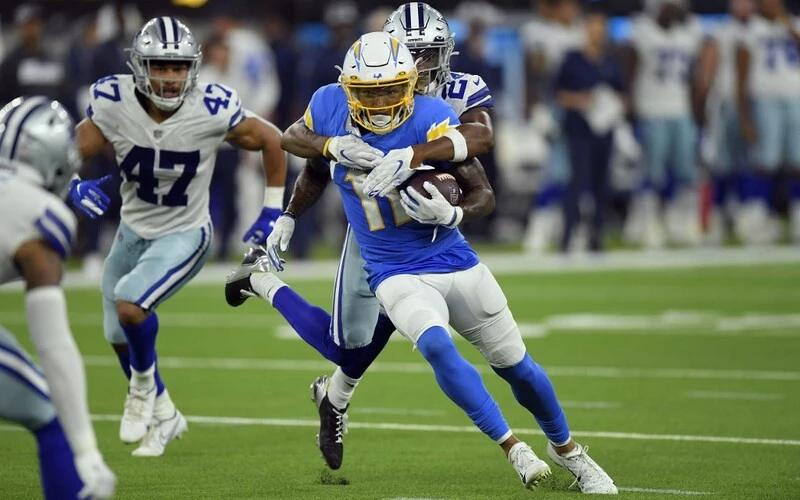 Jason Moore Jr. #11 of the Los Angeles Chargers is tackled by Israel Mukuamu #24 of the Dallas Cowboys during the second half of a pre season game at SoFi Stadium on August 20, 2022 in Inglewood, California.