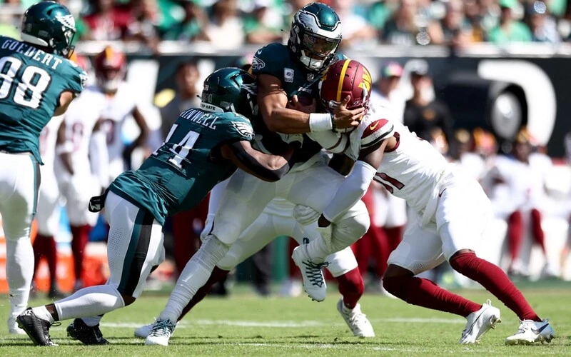 Kamren Curl #31 of the Washington Commanders tackles Jalen Hurts #1 of the Philadelphia Eagles as he rushes the ball during the second quarter at Lincoln Financial Field on October 01, 2023 in Philadelphia, Pennsylvania. The Eagles vs Commanders Betting Odds are set.