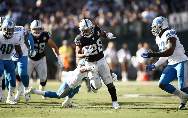 Josh Jacobs #28 of the Oakland Raiders tries to run past Will Harris #25 of the Detroit Lions at RingCentral Coliseum on November 03, 2019 in Oakland, California. The Raiders vs Lions Odds are already set for tonight's game.